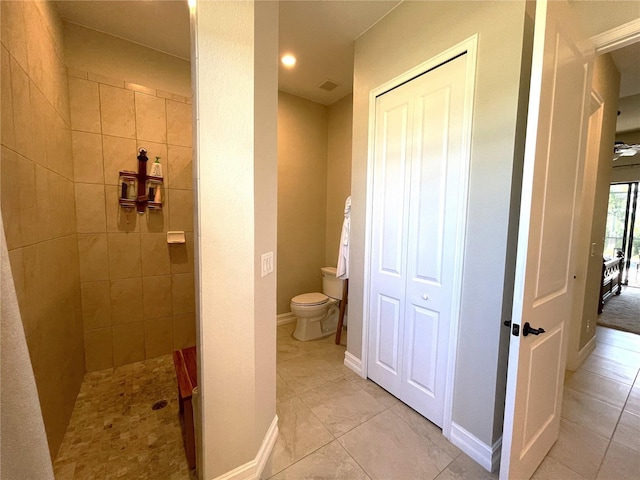 bathroom featuring tiled shower and toilet