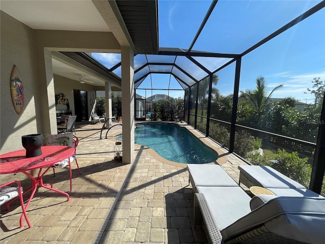 view of pool with a patio, ceiling fan, and glass enclosure