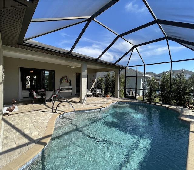 view of swimming pool featuring a patio, ceiling fan, and glass enclosure