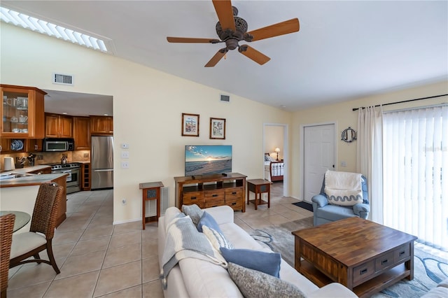 tiled living room featuring ceiling fan, sink, and vaulted ceiling