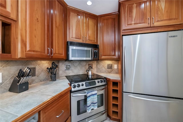 kitchen featuring tile countertops, stainless steel appliances, and tasteful backsplash