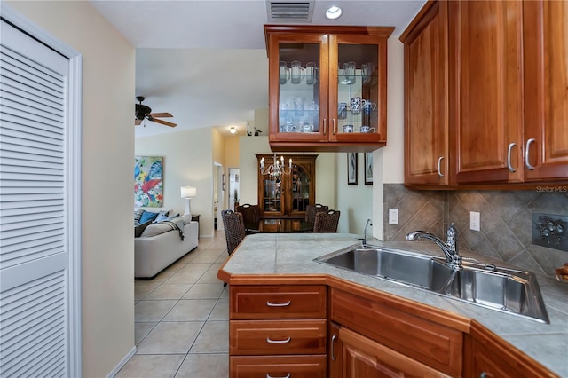 kitchen featuring decorative backsplash, vaulted ceiling, sink, light tile patterned floors, and tile counters