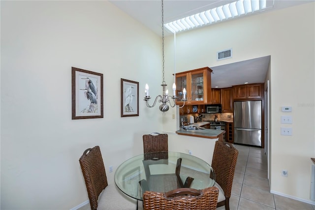 tiled dining room featuring an inviting chandelier, high vaulted ceiling, and sink