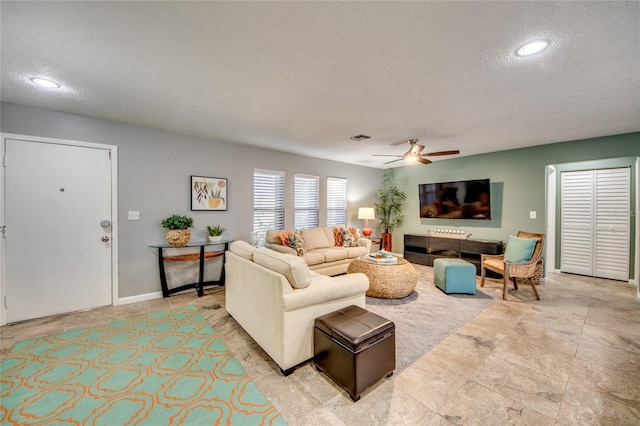 living room featuring ceiling fan and a textured ceiling