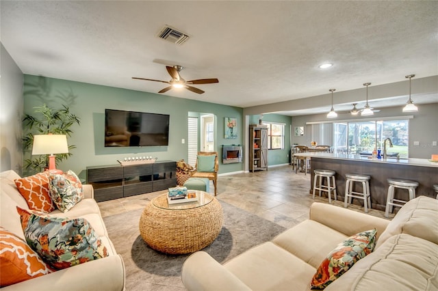 living room featuring a textured ceiling, ceiling fan, and sink