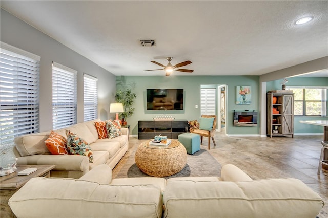 tiled living room with ceiling fan, a textured ceiling, and a wealth of natural light