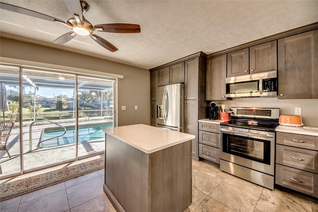 kitchen with ceiling fan, a center island, a textured ceiling, and appliances with stainless steel finishes