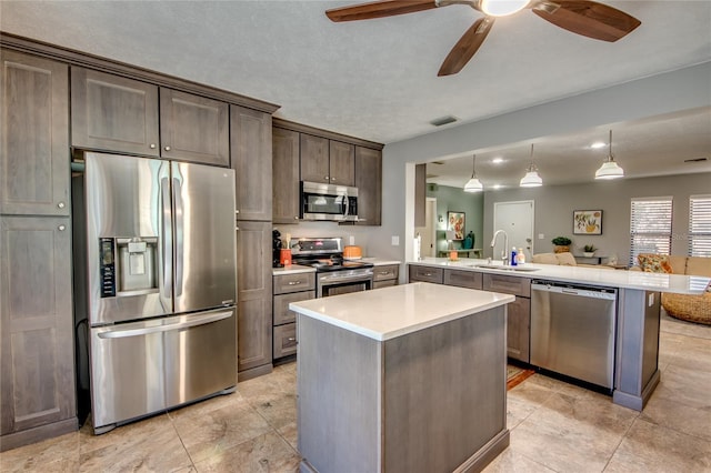 kitchen with dark brown cabinetry, sink, kitchen peninsula, decorative light fixtures, and appliances with stainless steel finishes