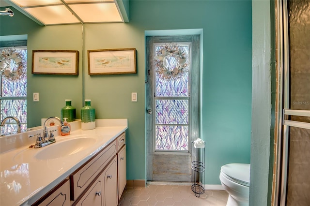 bathroom featuring toilet, vanity, tile patterned floors, and a wealth of natural light