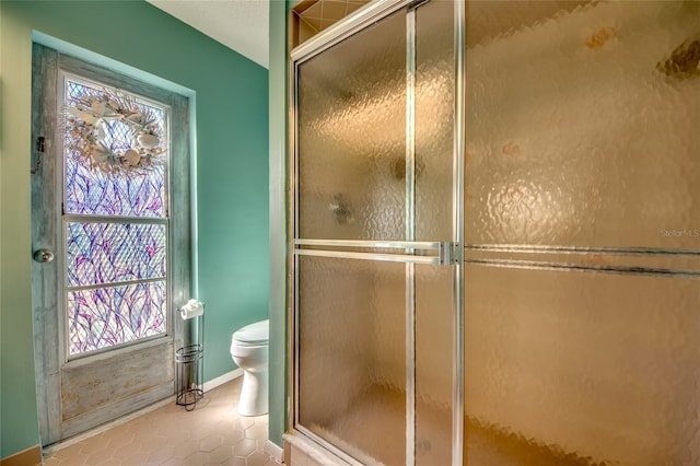 bathroom with tile patterned floors, toilet, and a shower with door