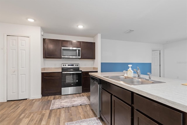 kitchen featuring sink, stainless steel appliances, dark brown cabinetry, and light wood-type flooring