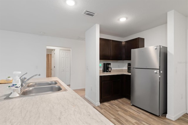 kitchen featuring stainless steel refrigerator, light hardwood / wood-style flooring, sink, and dark brown cabinetry