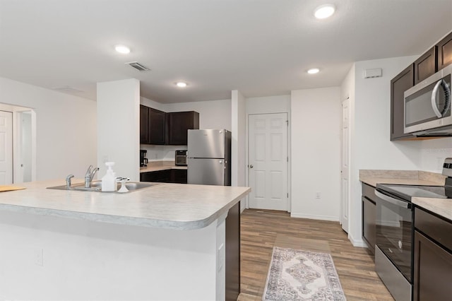 kitchen featuring sink, appliances with stainless steel finishes, dark brown cabinets, and light hardwood / wood-style floors