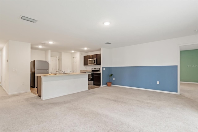 kitchen featuring an island with sink, light carpet, and appliances with stainless steel finishes