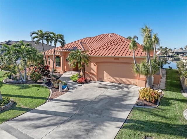 mediterranean / spanish-style house with a water view, a garage, and a front lawn