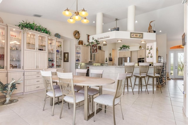 dining space featuring a notable chandelier, a towering ceiling, and light tile patterned floors