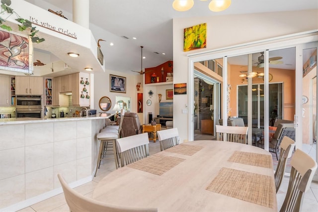 dining room featuring ceiling fan, light tile patterned flooring, and vaulted ceiling