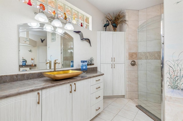 bathroom with tile patterned flooring, a tile shower, and vanity