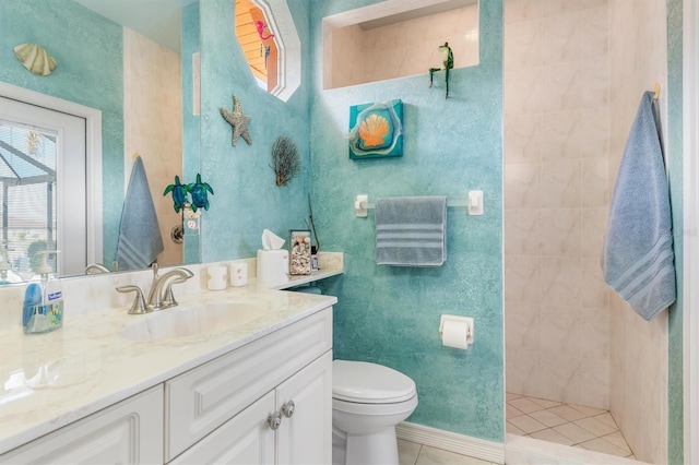 bathroom with tiled shower, tile patterned flooring, vanity, and toilet