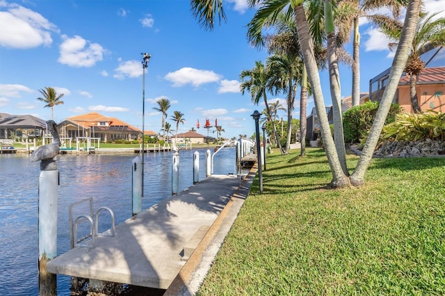 view of dock with a water view and a lawn