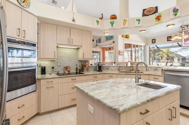 kitchen with light brown cabinets, a center island with sink, stainless steel appliances, and sink