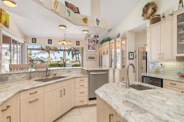 kitchen with light stone countertops, dishwasher, lofted ceiling, and sink