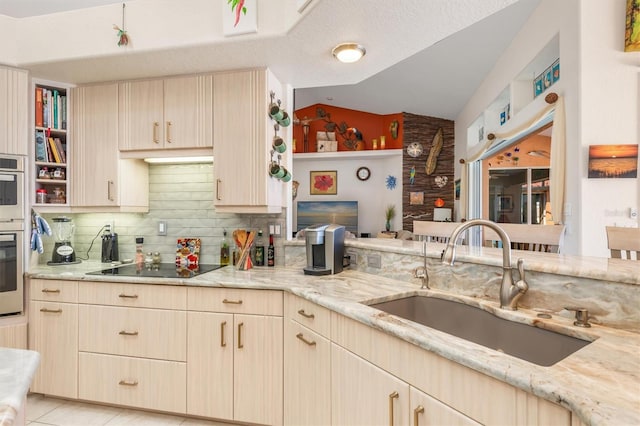 kitchen featuring sink, stainless steel oven, light stone counters, vaulted ceiling, and black electric cooktop