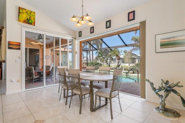 dining area featuring ceiling fan with notable chandelier, light tile patterned flooring, and vaulted ceiling