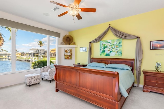 bedroom featuring ceiling fan, a water view, and light colored carpet