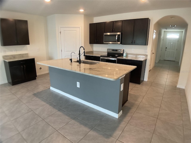 kitchen featuring a kitchen island with sink, sink, light tile patterned floors, and stainless steel appliances