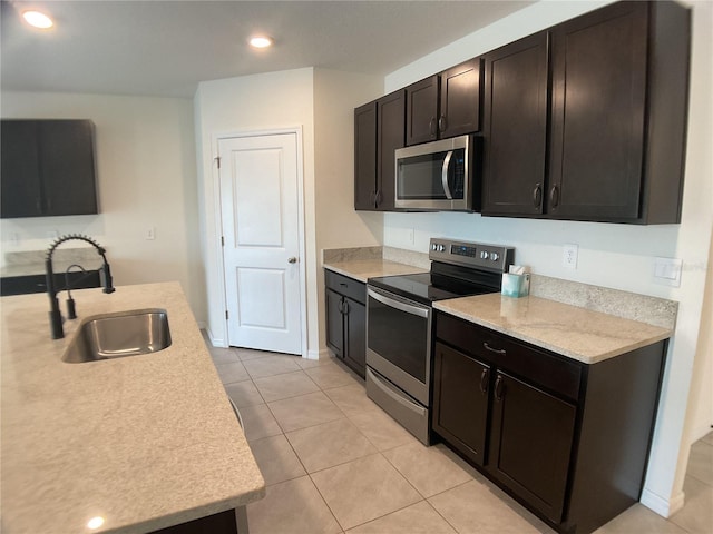 kitchen featuring appliances with stainless steel finishes, light tile patterned floors, dark brown cabinets, and sink