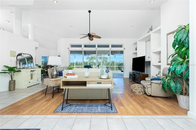 living room with ceiling fan, light hardwood / wood-style flooring, high vaulted ceiling, and built in features