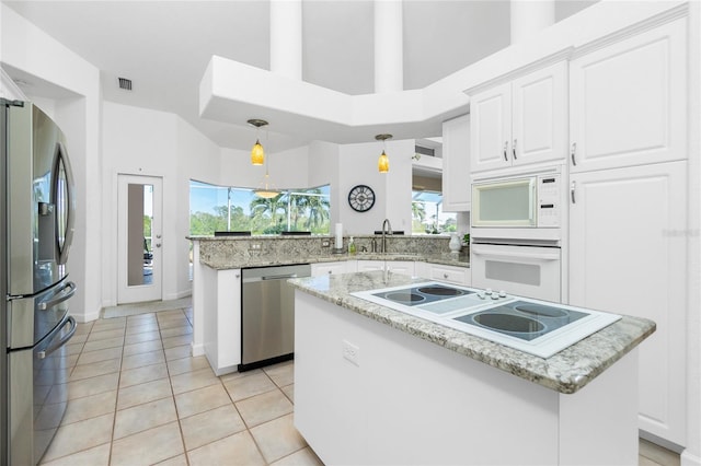 kitchen featuring appliances with stainless steel finishes, a healthy amount of sunlight, pendant lighting, a center island, and white cabinetry