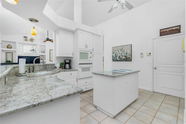 kitchen featuring light stone counters, sink, pendant lighting, light tile patterned floors, and white cabinets