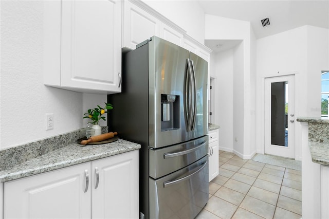 kitchen featuring white cabinetry, stainless steel fridge with ice dispenser, light tile patterned floors, and light stone counters