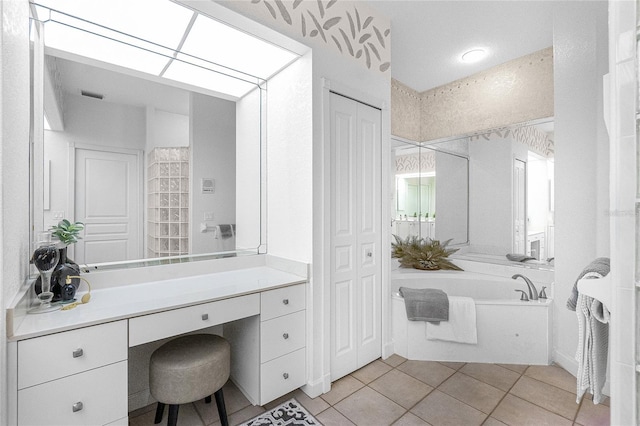 bathroom with a washtub, vanity, and tile patterned flooring