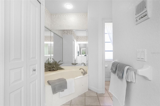 bathroom featuring tile patterned floors, a tub to relax in, and a textured ceiling