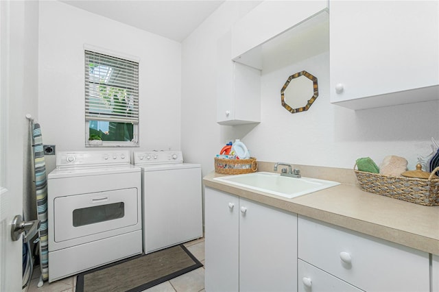 clothes washing area with cabinets, washing machine and dryer, light tile patterned flooring, and sink