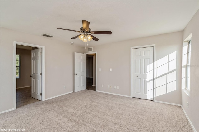 unfurnished bedroom featuring light carpet, multiple windows, and ceiling fan