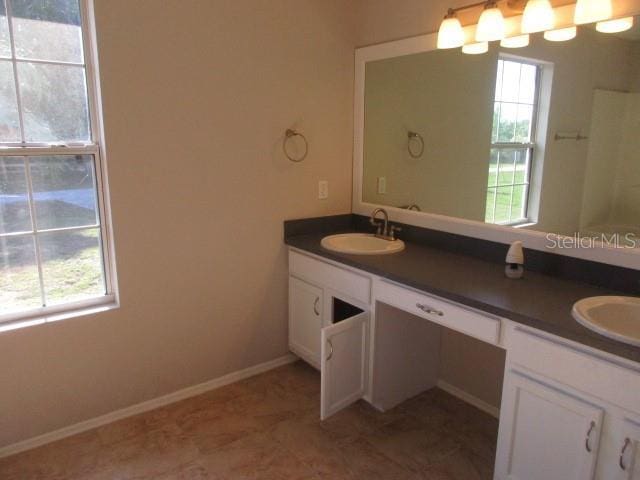 full bath with double vanity, plenty of natural light, and a sink