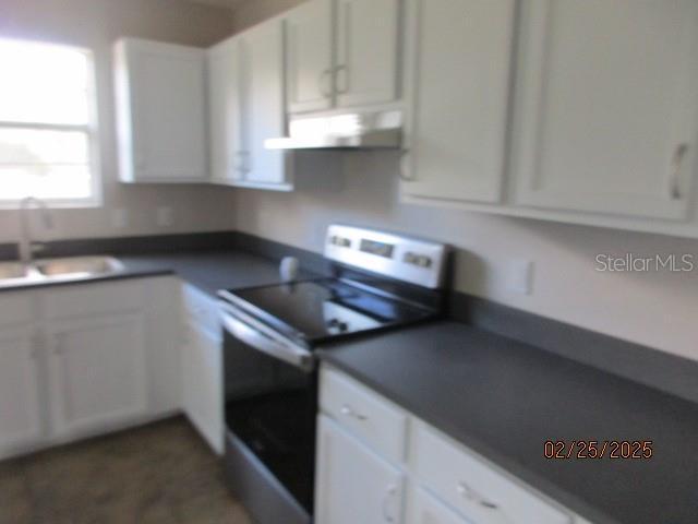 kitchen featuring white cabinets, under cabinet range hood, and stainless steel electric range