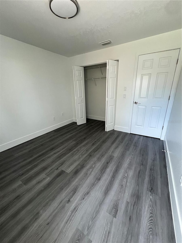 unfurnished bedroom with a closet and dark hardwood / wood-style flooring