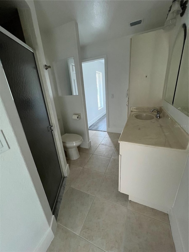 bathroom featuring tile patterned floors, vanity, an enclosed shower, and toilet