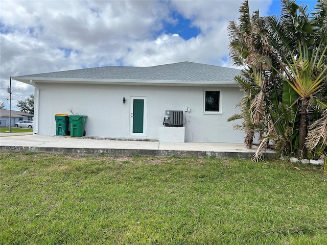 back of property featuring central air condition unit and a yard