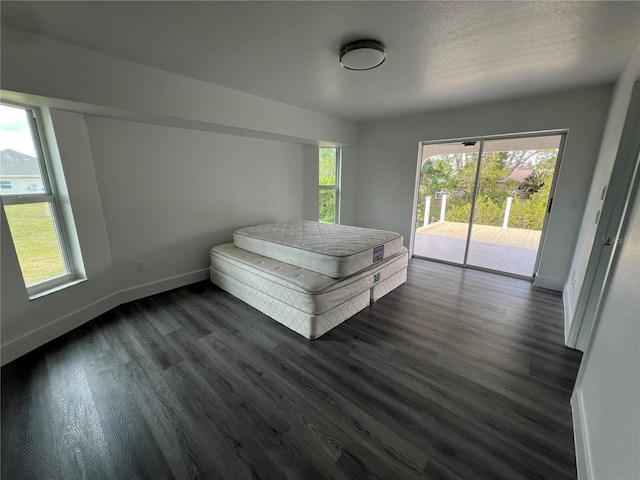 unfurnished bedroom with access to exterior, dark hardwood / wood-style flooring, and multiple windows