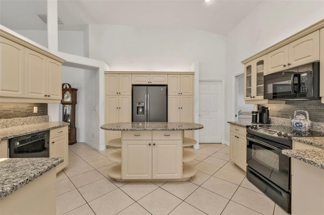 kitchen with tasteful backsplash, high vaulted ceiling, light stone countertops, a kitchen island, and black appliances