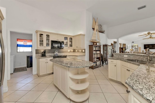 kitchen featuring ceiling fan, sink, light stone counters, and cream cabinetry