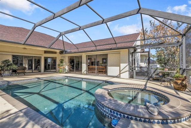 view of pool with a patio, glass enclosure, and an in ground hot tub