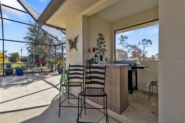 view of patio with glass enclosure, a grill, and an outdoor bar