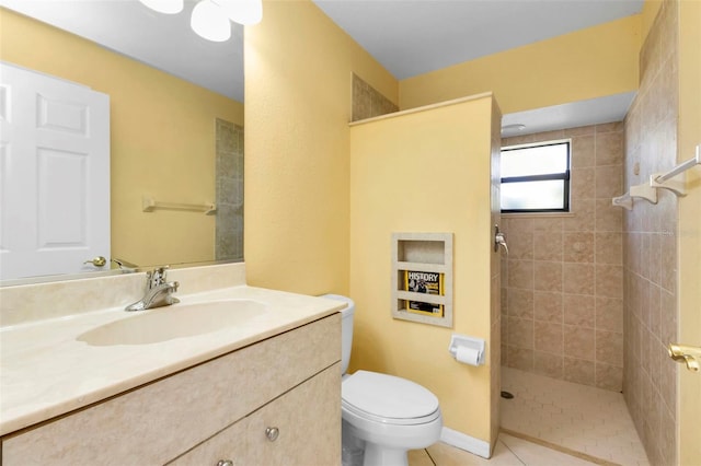 bathroom featuring toilet, vanity, tile patterned flooring, and tiled shower